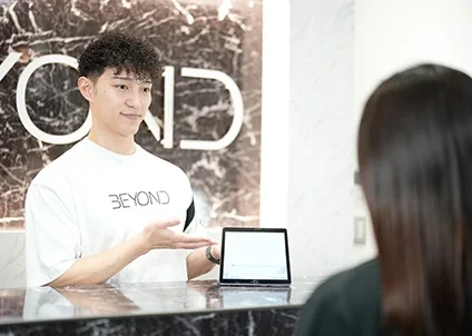 BEYONDの受付でトレーナーが利用者を案内する様子